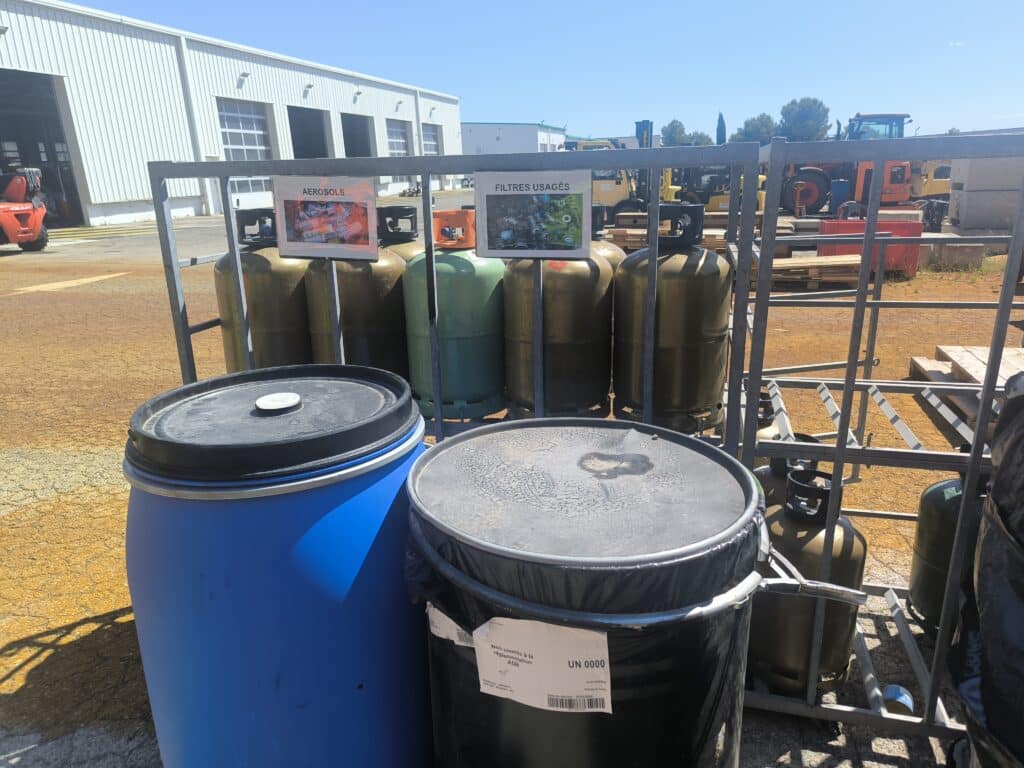 Zone de tri sélectif avec barils et bouteilles de gaz.