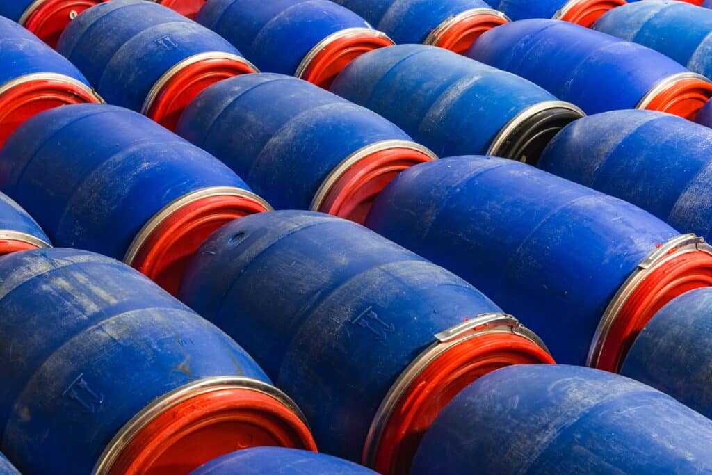 Nombreux fûts industriels bleus et rouges empilés en motif diagonal.